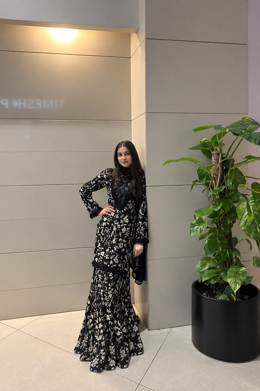 Midnight Bloom black floral lawn sharara set shown in a side standing pose with flared trousers and coordinated printed shirt