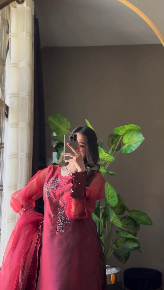 Murraya Maroon katan silk three piece outfit in a side pose with organza dupatta, crystal chain accents and maroon formal styling