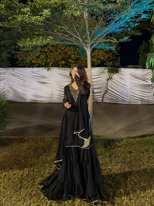 Black chiffon Rang-e-Shabnam ensemble showing layered gharara, ring sleeves and dupatta in an outdoor portrait