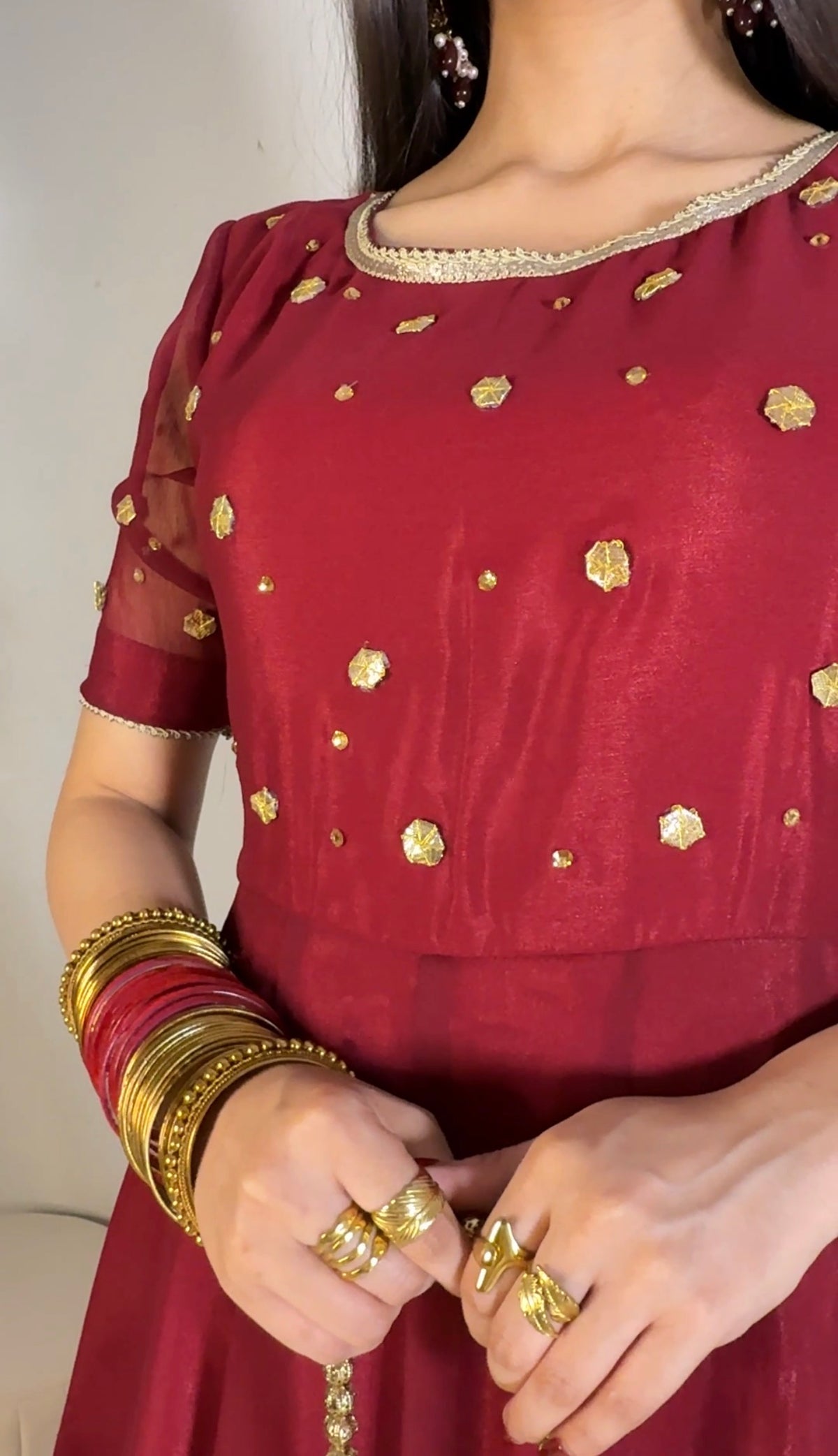 Close crop of Aatish maroon chiffon frock highlighting the rounded neckline, gold motifs and short sleeves