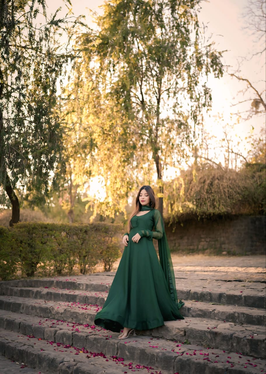 Wide outdoor view of Abroo green chiffon frock on stone steps with full flowing silhouette, long sleeves and matching dupatta