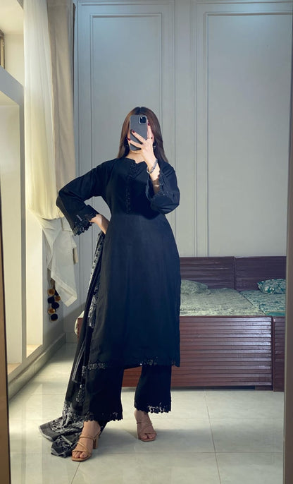 Black Aura lawn three piece outfit in a hand-on-waist pose with black straight shirt, matching trousers and patterned jacquard dupatta