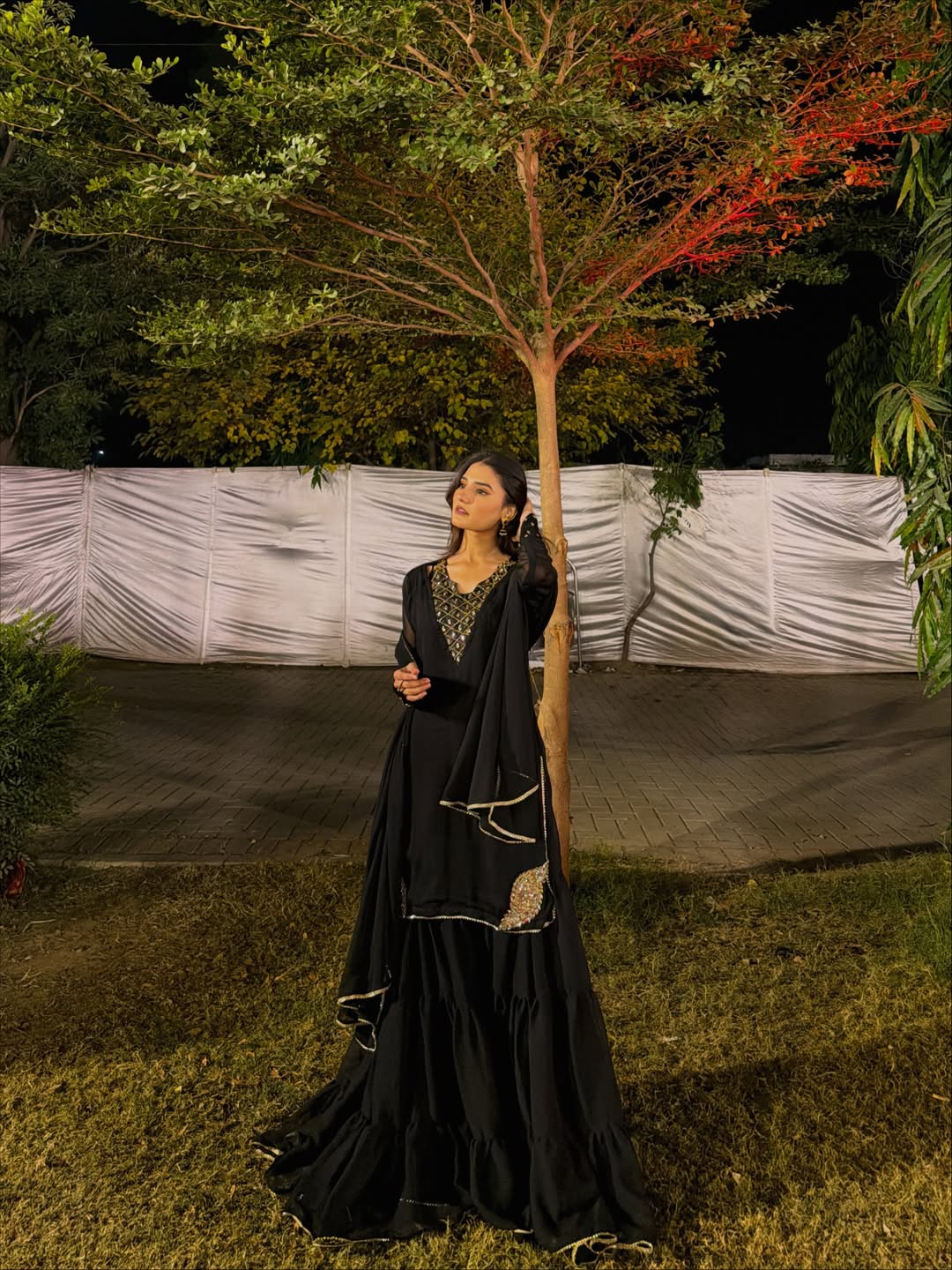 Rang-e-Shabnam black chiffon outfit featuring a flowing layered gharara and dupatta in a garden setting