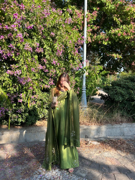 Murrayya leaf green 3 piece in an outdoor side pose with flowing organza dupatta and long silk shirt