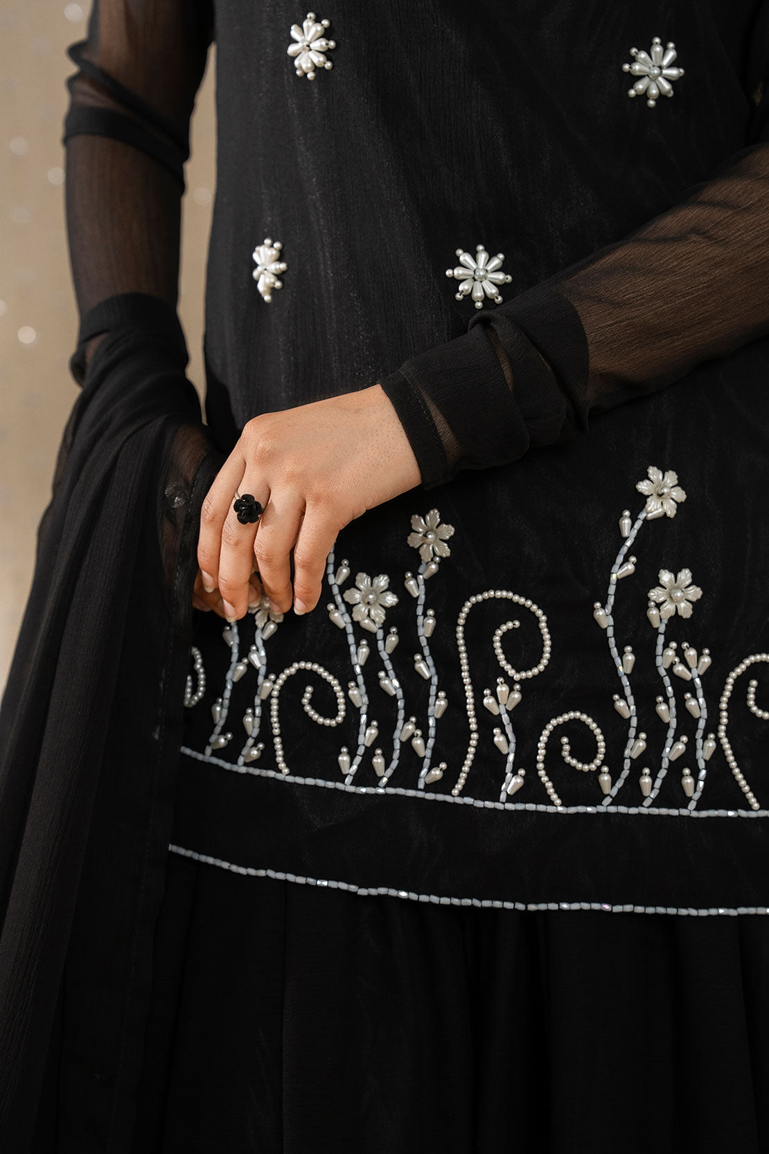 Detailed view of white floral embroidery on Noir Zahra black chiffon shirt and sheer sleeves