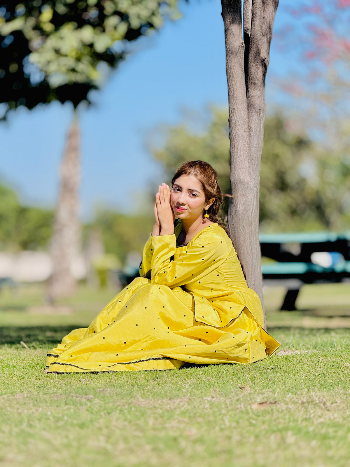 Primrose yellow raw silk kalidar lehenga set in seated outdoor pose by AnabiyawearPrimrose yellow raw silk kalidar lehenga set in seated outdoor pose by Anabiyawear