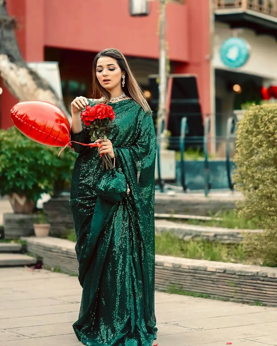 Snowdrop Bottle Green sequin net saree in outdoor standing pose with draped pallu by Anabiyawear